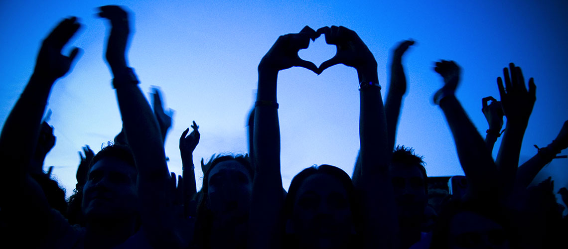 signe du coeur avec les mains dans la foule du public de soliays, fond bleu 